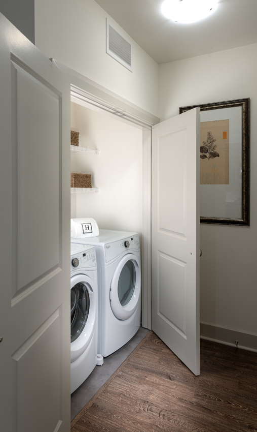 White washer and dryer set in a lit laundry room.